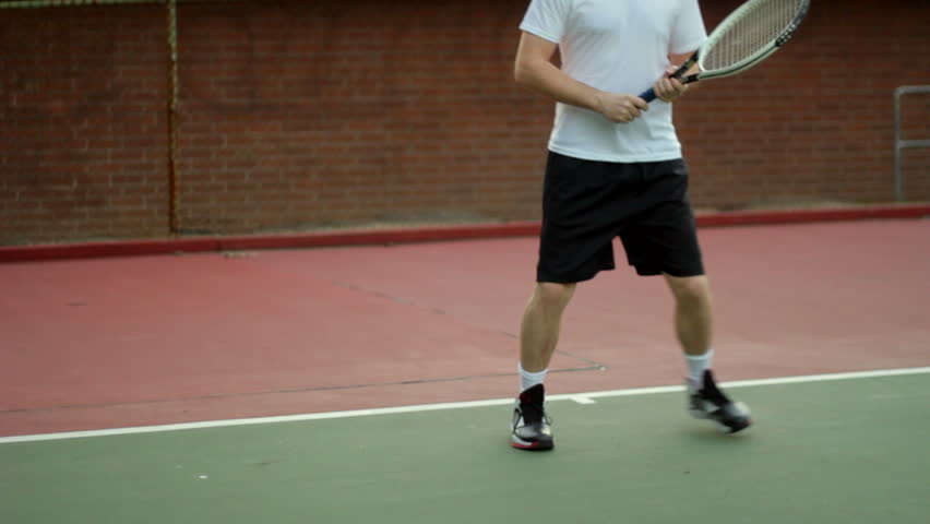 A tennis player runs back and forth in frame, returning various shots.