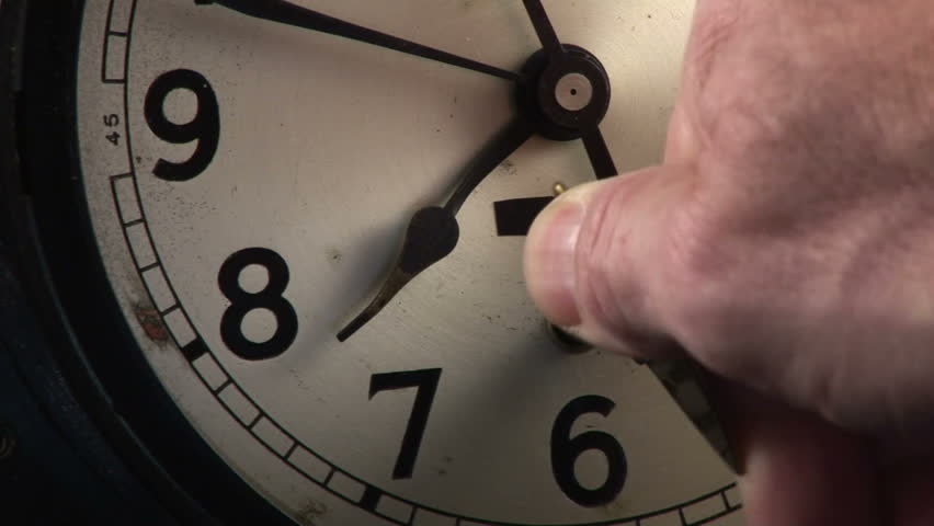 A close up of a man winding an old shipÃ¢â¬â¢s clock