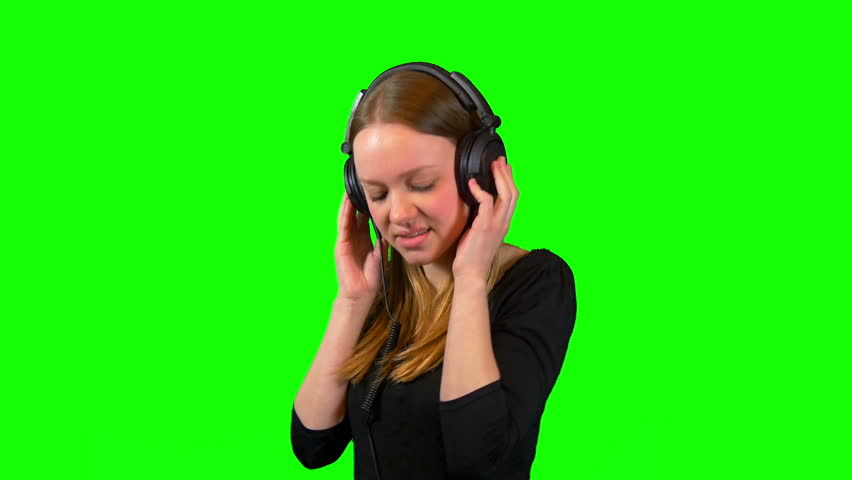 A Woman Moving To The Music On Her Headphones In Front Of A Green Background Stock Footage Video