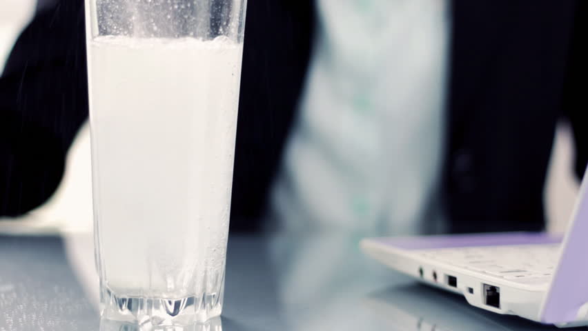Woman pouring water into glass and adding effervescent tablet