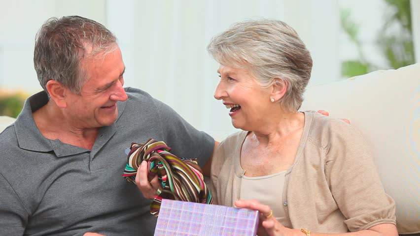 Man offering a scarf to his wife in the living room
