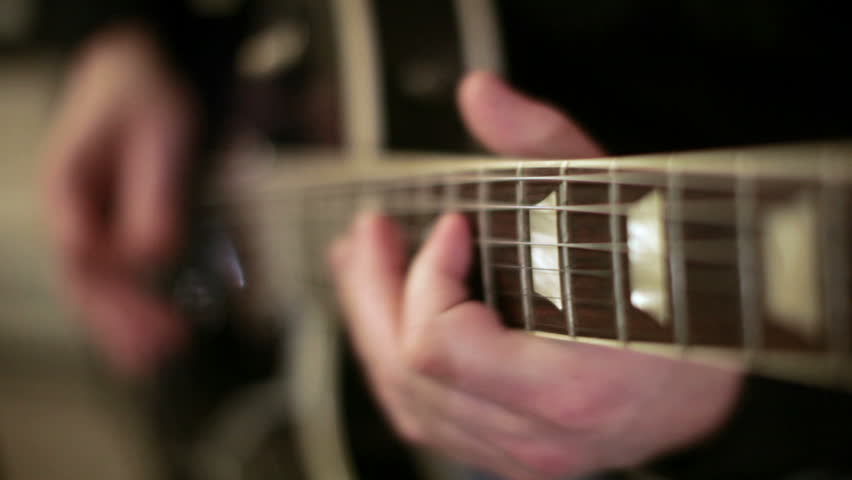 A shallow depth of filed look at a guitar is being played