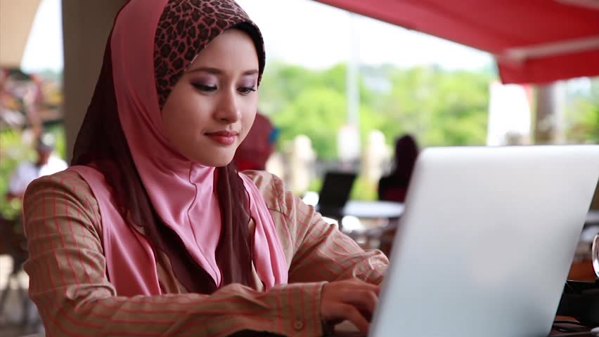 Young Muslim Girl using laptop and smiling at the camera