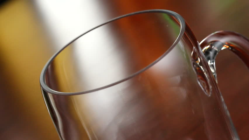 A bottle of beer is poured into a mug in a bar