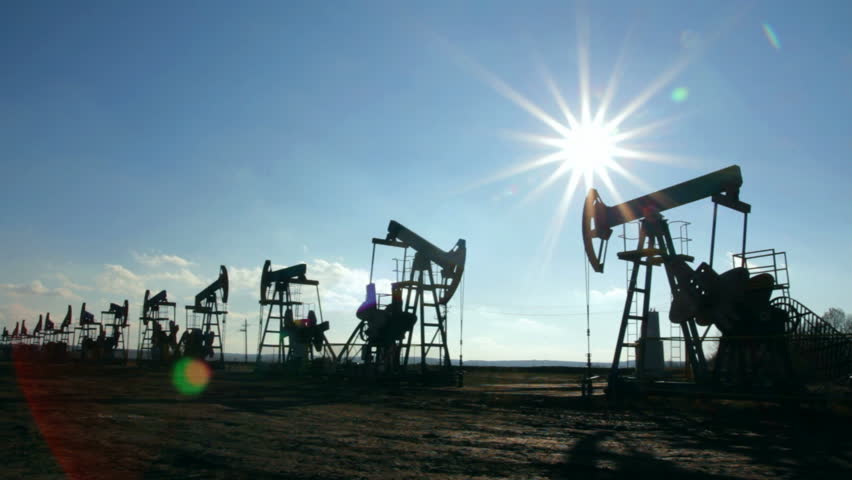 working oil pumps silhouetted against sun