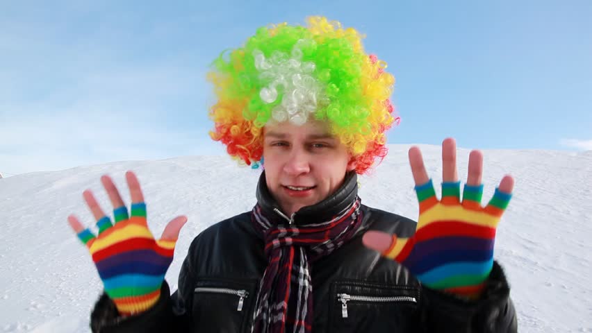 The man in colored wig does funny movement against the slope