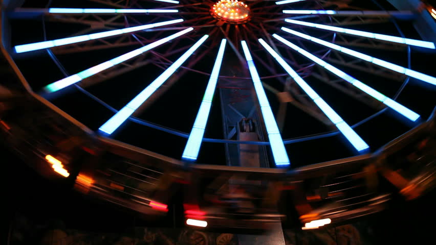 Colorful illuminated spinning wheel in amusement park at night