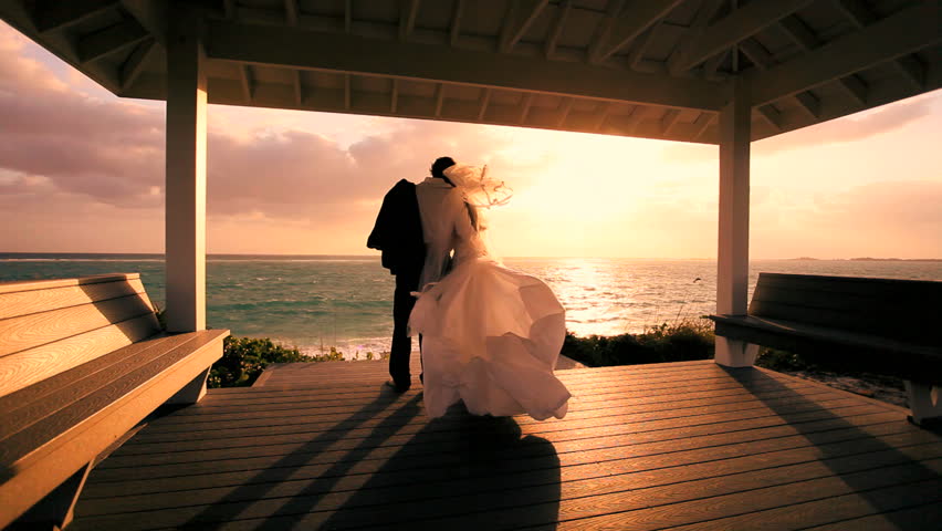 Loving caucasian couple watching the sunset after their oceanside island wedding