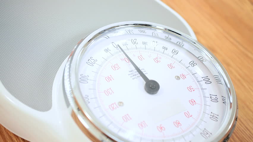Pair of feet in close-up stepping onto a pair of weighing scales