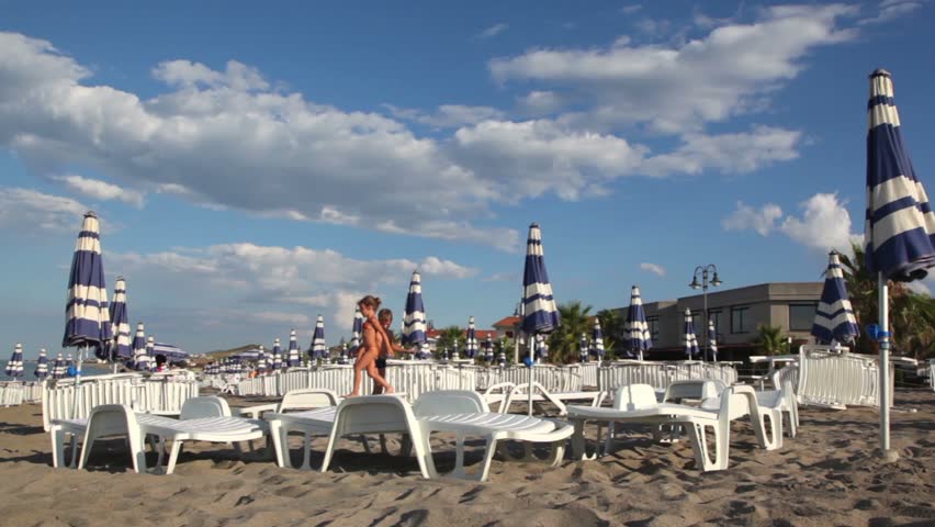 two children play on deckchairs jumping from one to another, then comes the third child and does the same thing