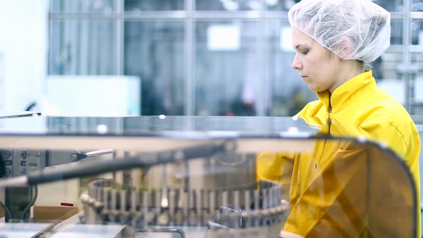 A female technician is monitoring the work of pharmaceutical machine .  HD 1080i. 
