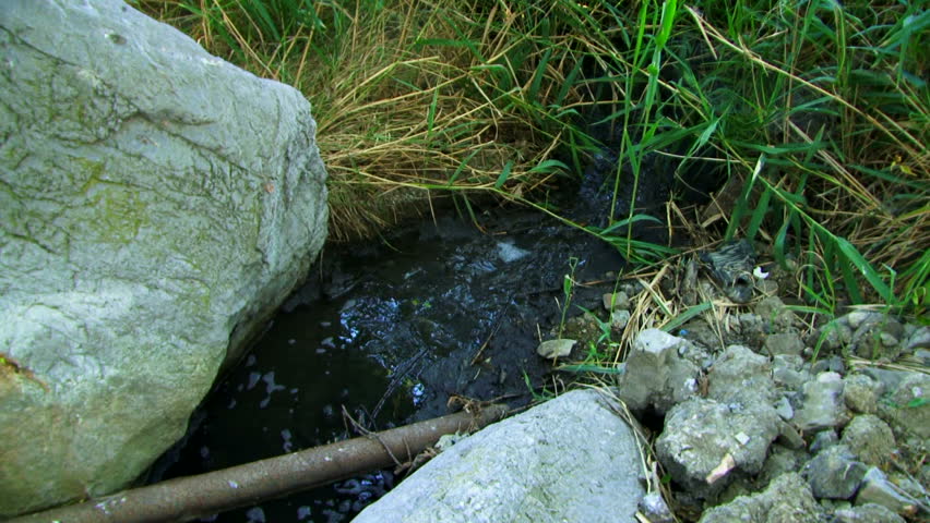 Unknown pollution. From an old rusty pipe follows an unknown substance.