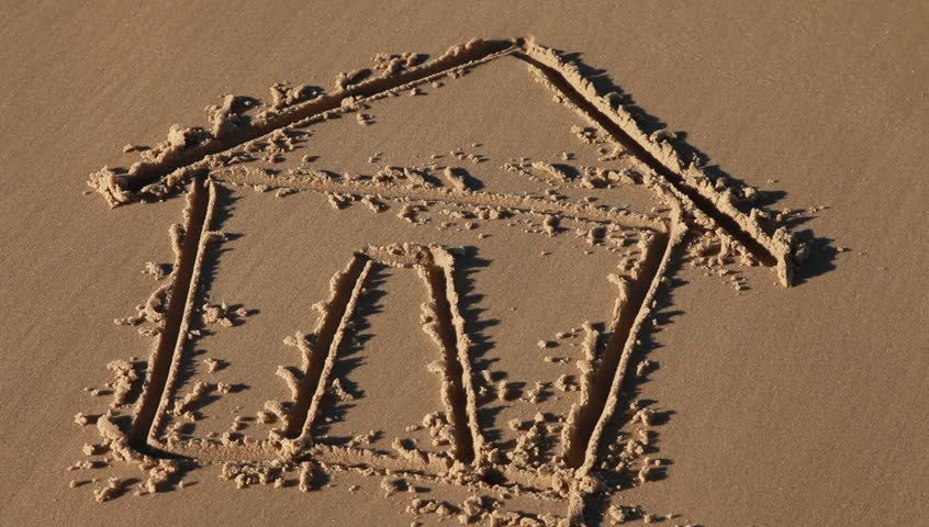 a house drawn in the sand gets washed away by a wave