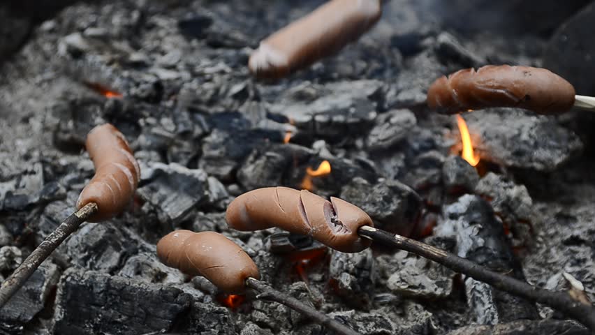 Grilled sausages over campfire