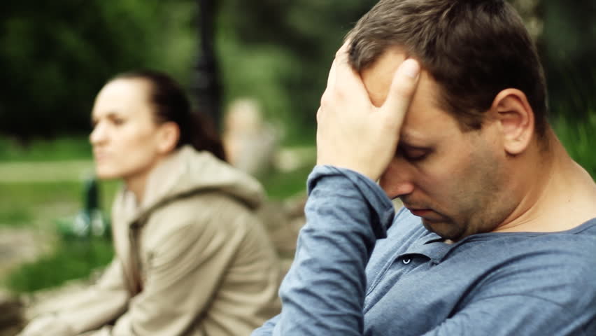 Relationship difficulties, young couple sitting on bench in the park