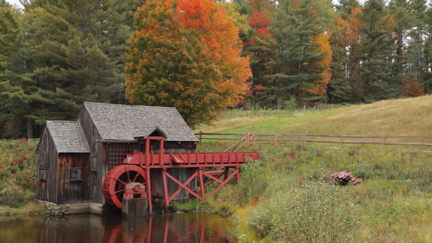 Pan of an old grist mill near Guildhall, Vermont with brilliant Fall foliage in the background.