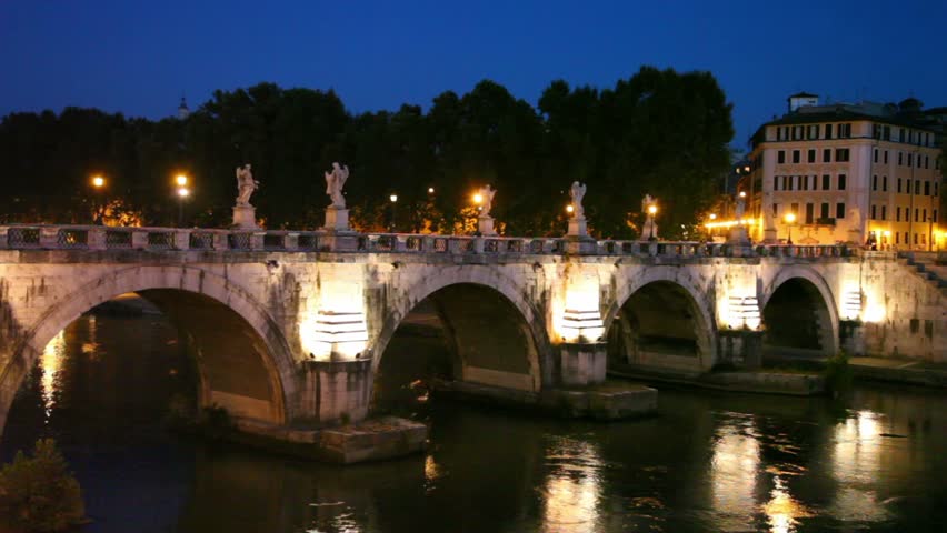 People walk along Sant Angelo Bridge at night, river flow are also shown