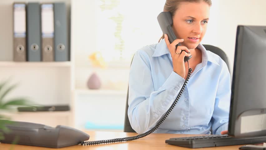 Charming office working answering the phone in her office