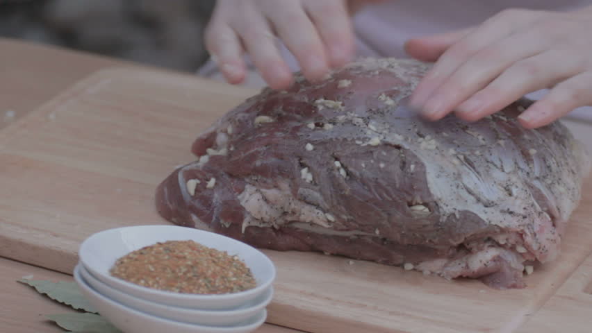 EDIT MULTICAM VIDEO Woman Sprinkling on top and carefully rubbing the surface  of fat piece of pork with mixed spicy kitchen herbs. 
