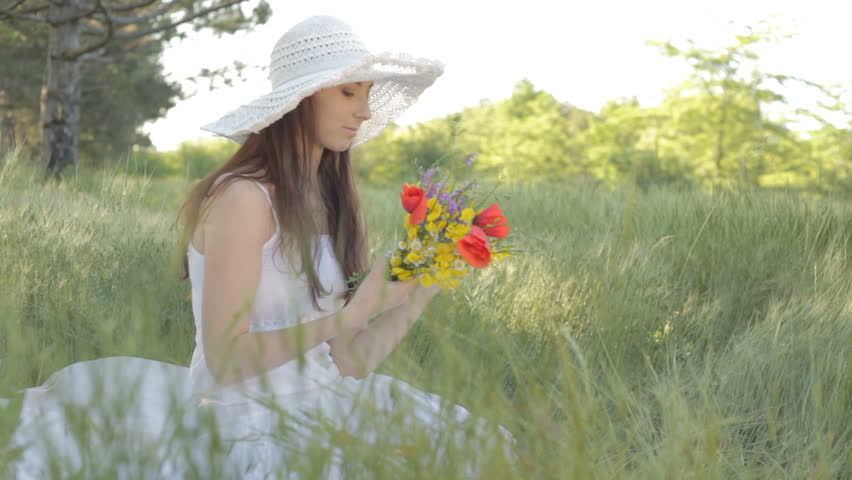 Young woman with bouquet of wild flowers in nature 