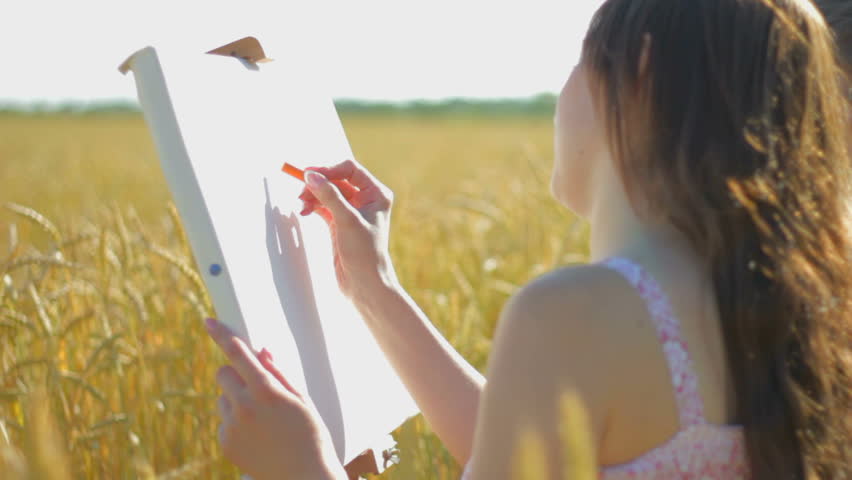 Young woman with boy drawing with crayons in the field  