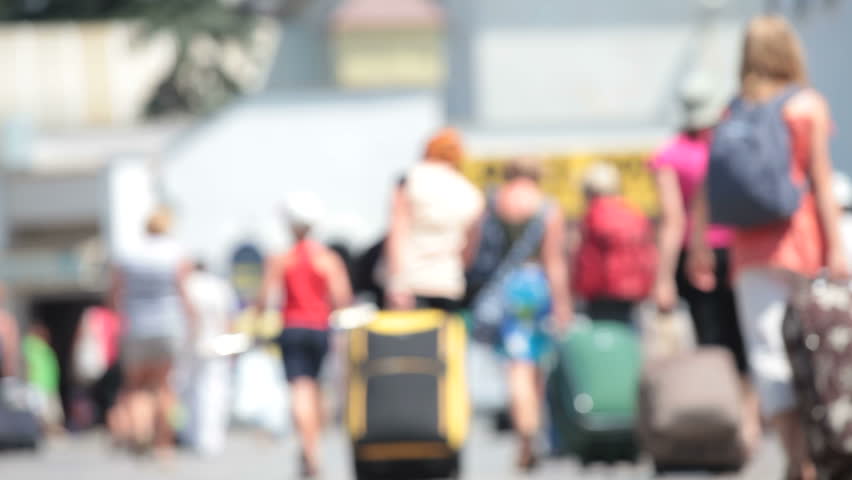 anonymous people with suitcases walk along the station platform