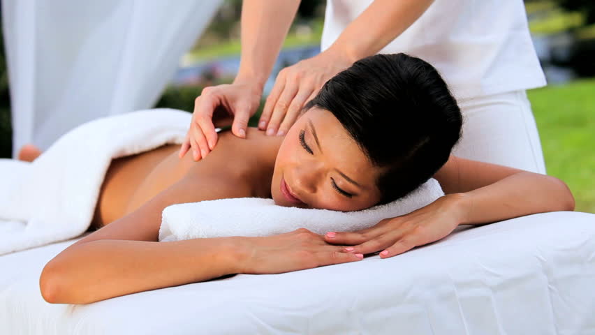 Young asian girl enjoying massage therapy outdoors at a luxury health spa
