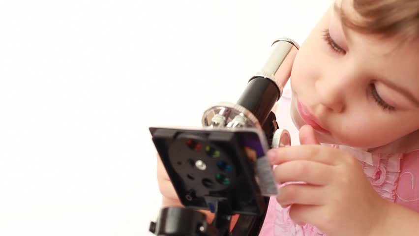 Little girl works with microscope making some research