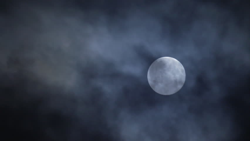 Full moon hiding by the clouds on dark night sky background - long shot