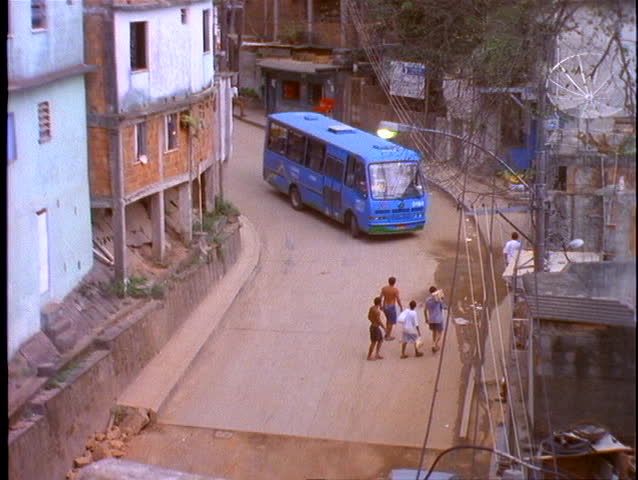 A blue bus travels on a street in a slum area of Rio De Janeiro, Brazil.