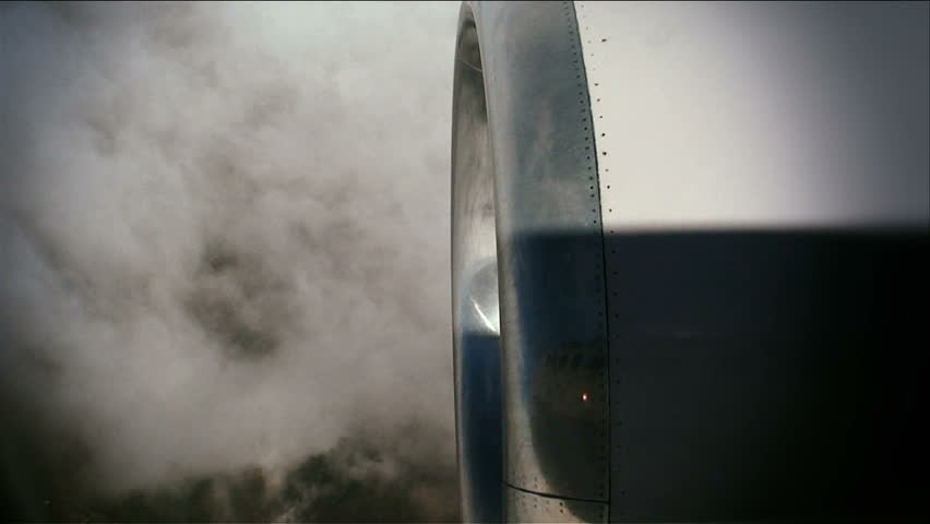Plane engine in foreground, clouds below