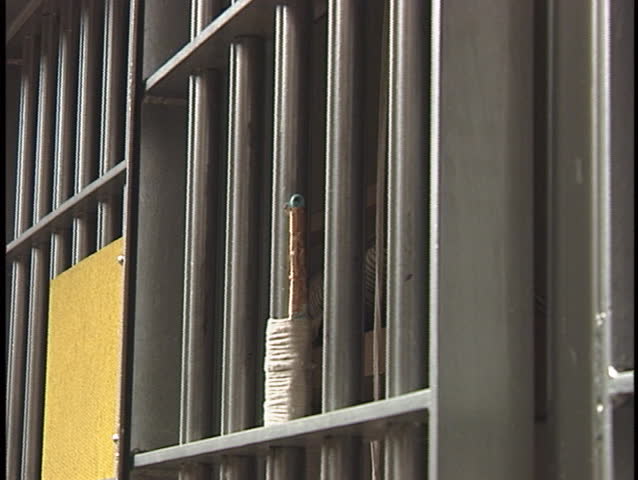 A prisoner places a letter between the bars on his prison-cell.
