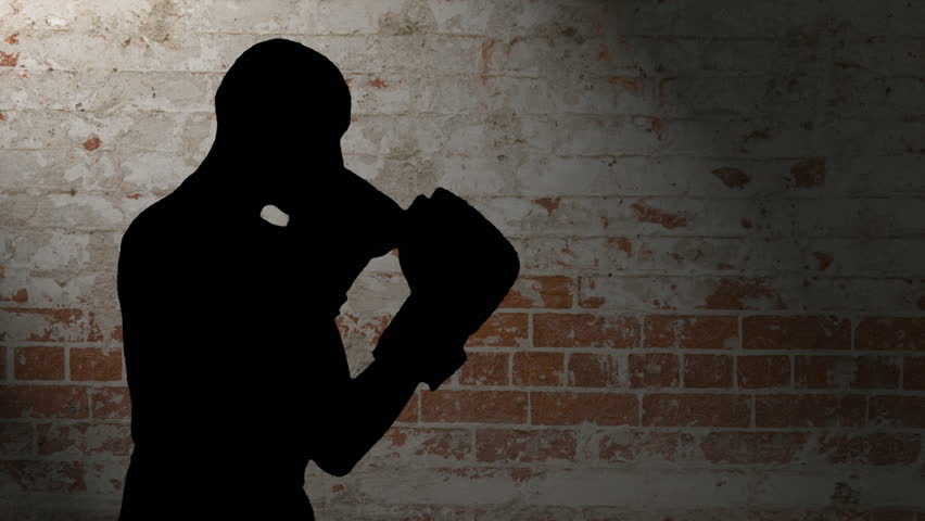 HD silhouette footage of a bald man wearing boxing gloves throwing various punches against a brick background