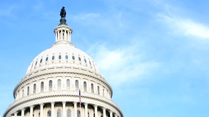 The white dome of the United States Capitol Building contrasts against a blue sky.