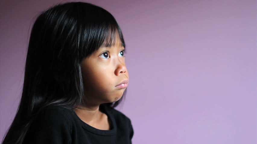 A cute little upset Asian girl is comforted by her teddy bear.