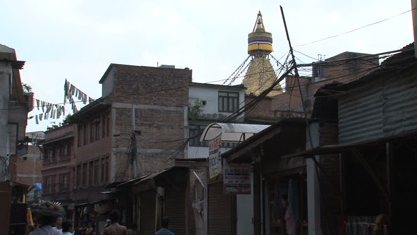KATHMANDU - CIRCA 2010: People circulate through the city with the Boudhanath Stupa temple in the background circa 2010 in Kathmandu.