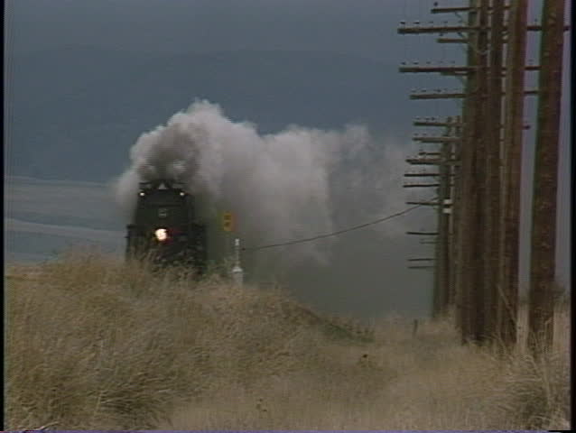 Tracking-out shot of steam billowing from a old-fashioned steam train.