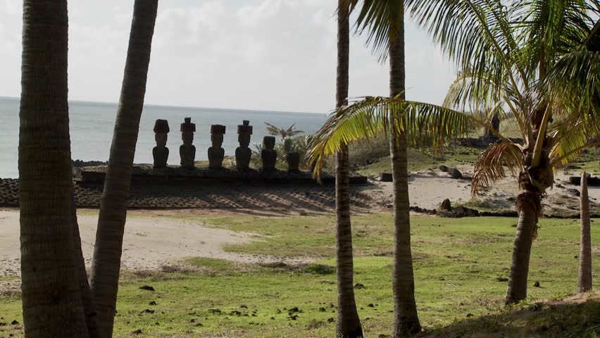 Easter Island statues stand in a long row on a distant beach.