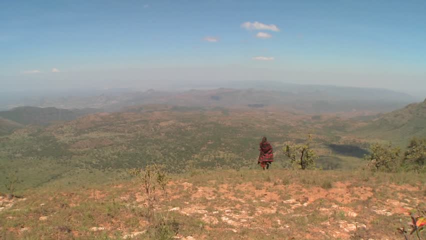 A masai warrior walking along a vast landscape in Northern Kenya.