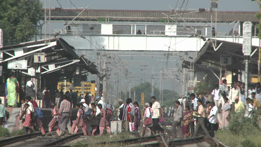 INDIA - CIRCA 2010: Crowds of people walking across a train-station's tracks circa 2010 in India.