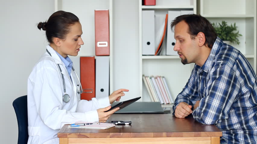 Female doctor explaining something on tablet computer to male patient
