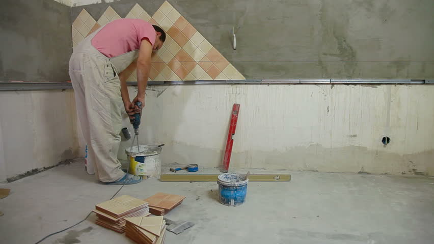 man installs ceramic tile - mixing grout, Wide Angle, Rear View