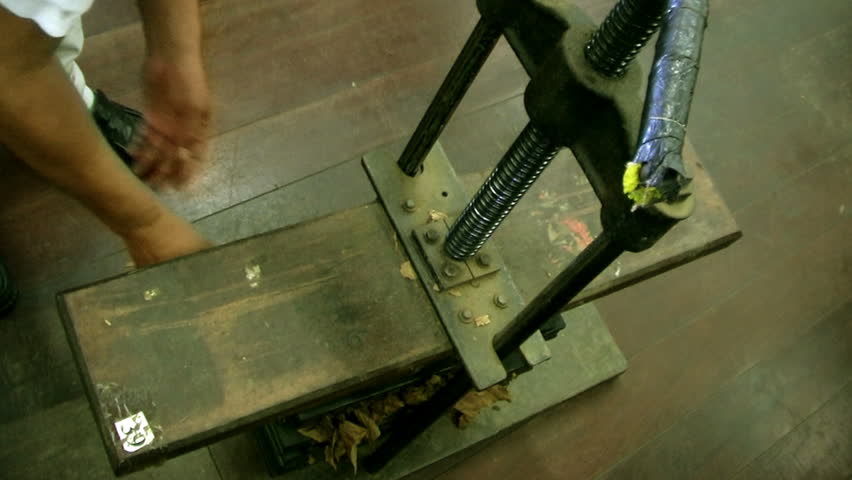 A cigar artisan press the cigar to create final shape.