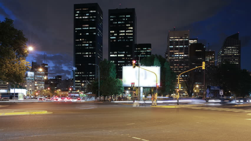 Traffic at a large street intersection at central Buenos Aires. Photo time-lapse, slight shift from dusk to night. Billboards and TM signs on buses have been blurred  (Argentina, Oct 2011, DSLR).