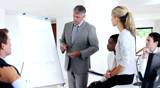 Mature business man giving presentation through graph to team in meeting