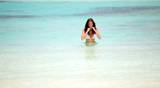 Portrait of gorgeous woman in bikini walking on beach 