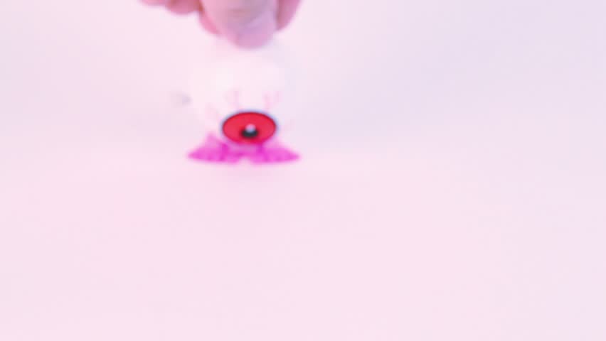 Finger push clockwork toy veiny eye from above and it begin jump forward, then backward