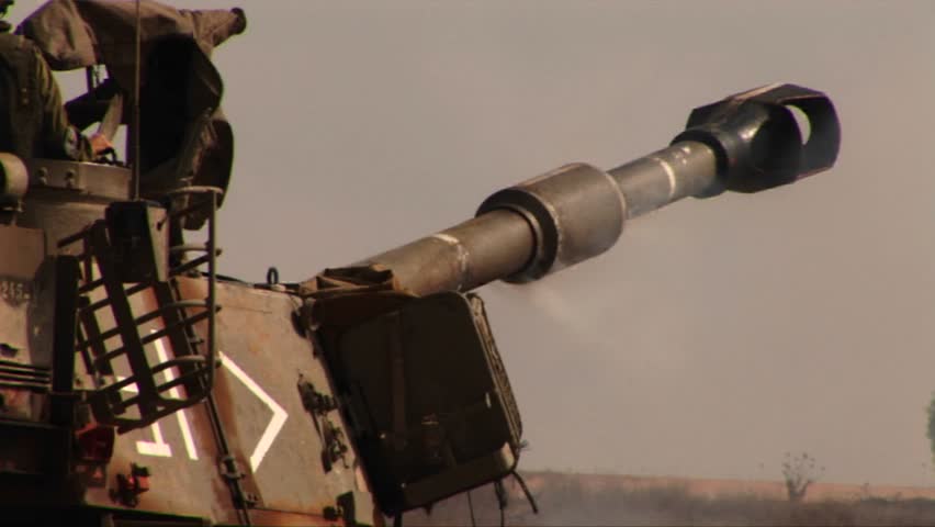 An army tank fires and recoils on a battlefield in the Middle East
