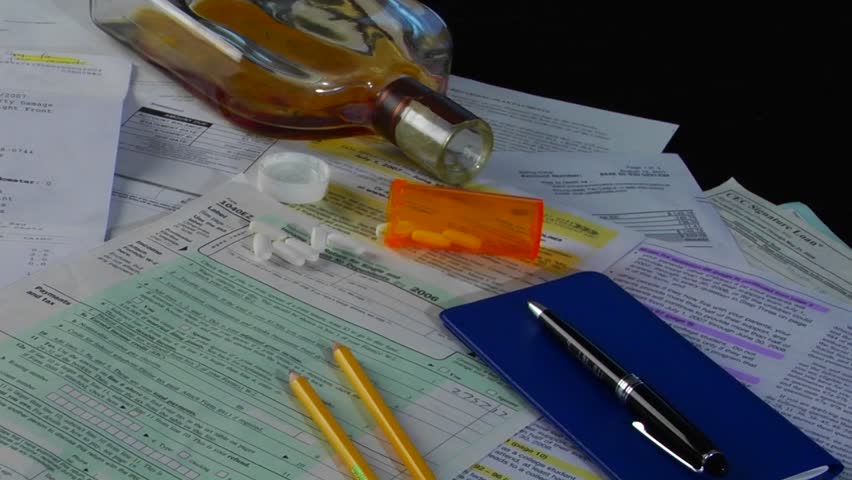 checkbook, accompanied by a glass of liquor and pills