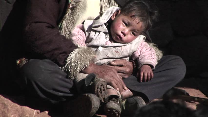 CHINA - CIRCA 2009: A small child sits in a poor beggars arms circa 2009 in China.